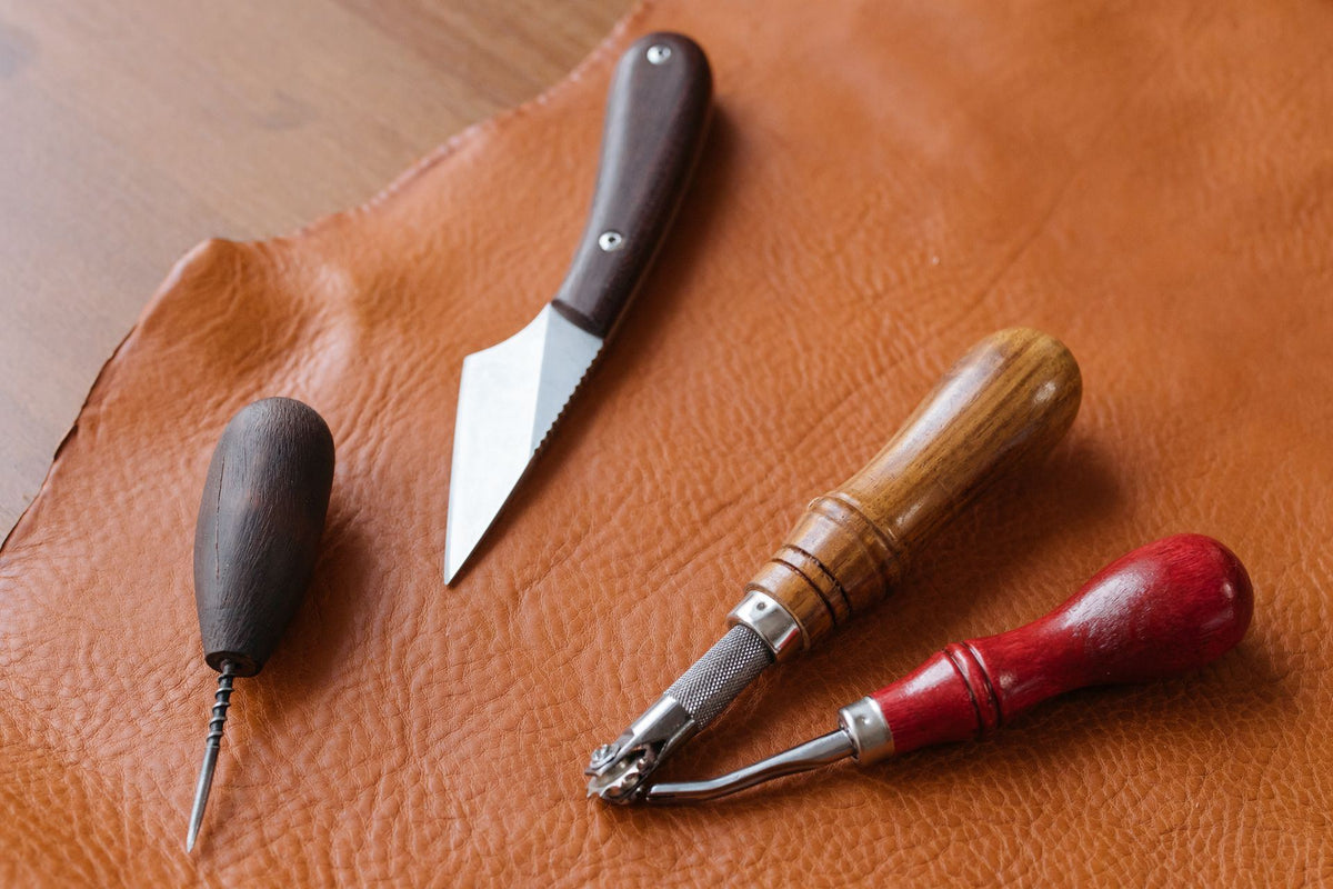 Leather-working tools resting on a tan leather hide