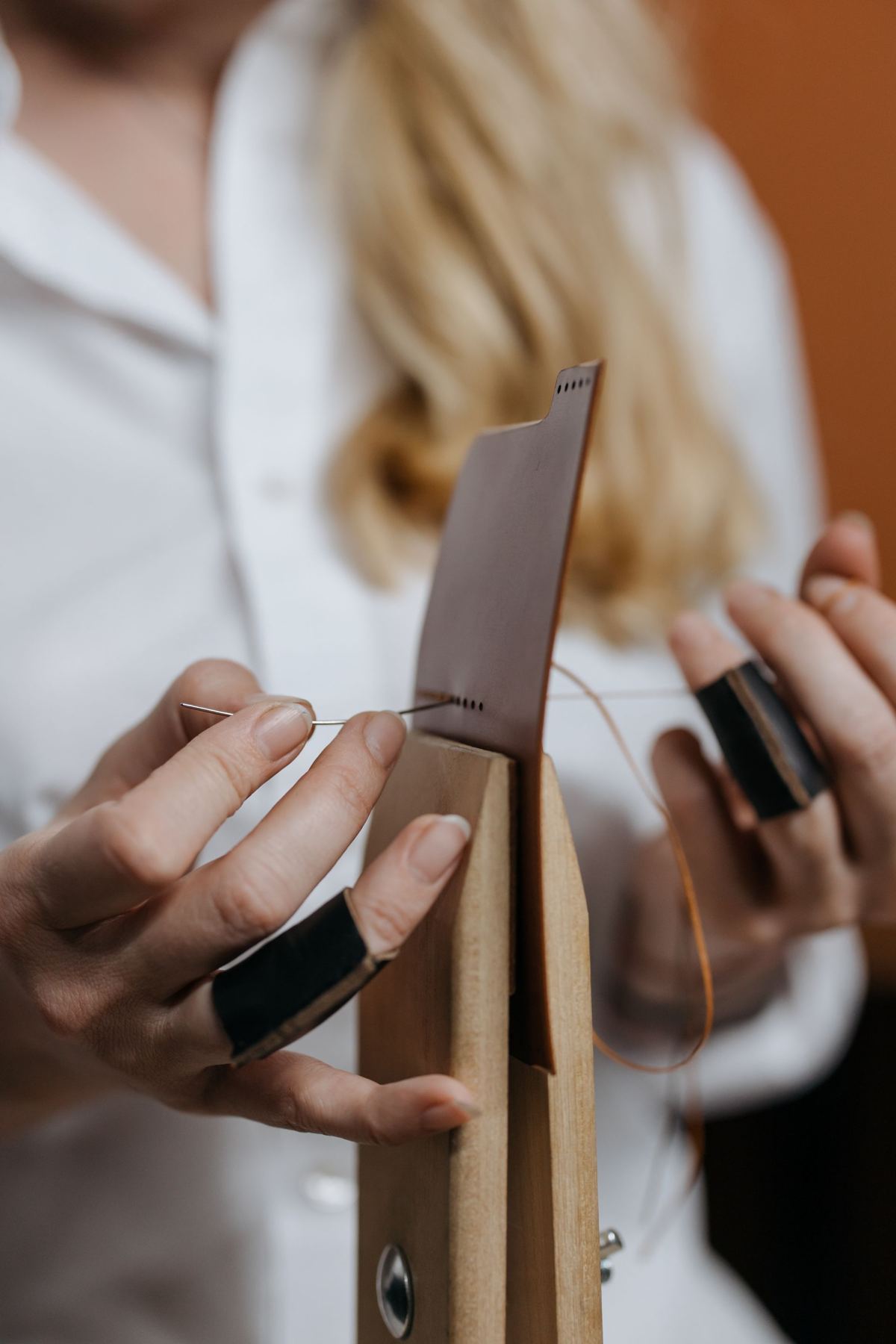 Hands stitching a piece of brown leather